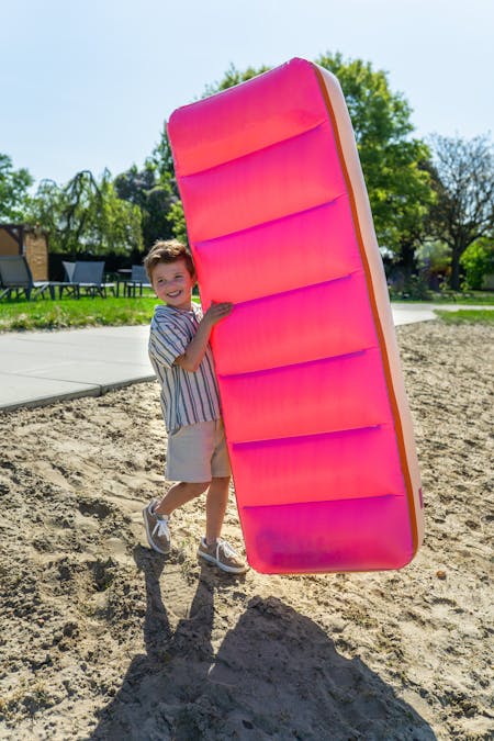 Foto van jongen met een roze opblaasbed