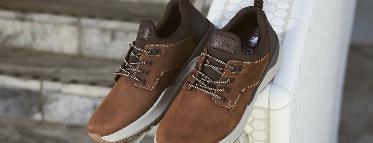 Comfortabele bruine Rieker herenschoenen met sportieve witte zool en donkere details, ideaal voor zowel casual als nette outfits.