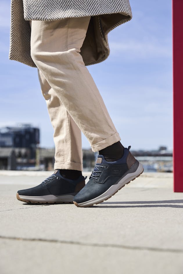 Stijlvolle blauwe Rieker herensneakers met bruine details en stevige witte zool, ideaal voor een casual en comfortabele look.